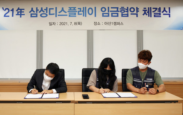 삼성디스플레이 아산캠퍼스에서 열린 '2021년 임금협약 체결식'에서 노사 위원들이 협약서에 서명하고 있다. 사진=삼성디스플레이 제공 (왼쪽부터) 김범동 삼성디스플레이 인사팀장, 김정란·이창완 노조 공동위원장