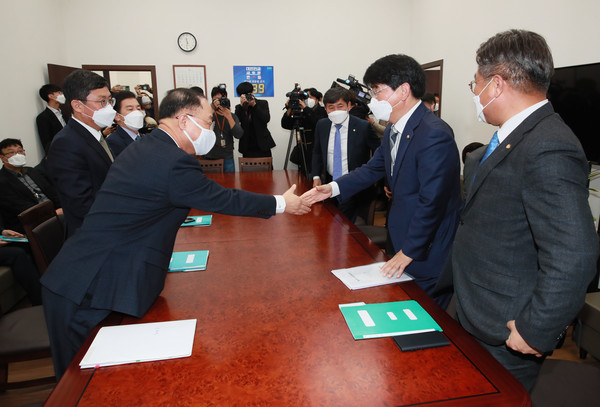 홍남기 경제부총리(왼쪽)와 더불어민주당 박완주 정책위의장이 30일 서울 여의도 국회 더불어민주당 원내대표실에서 예산협의를 위해 만나 악수하고 있다.(사진 연합뉴스 제공)