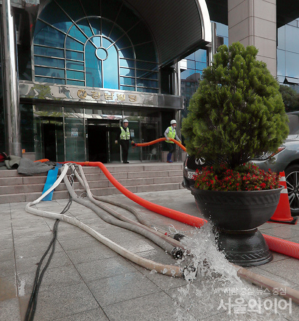 8~9일 이틀간 쏟아진 폭우로 건물 지하에 물이 찬 가운데 건물 관계자들이 물을 빼내고 있다.
