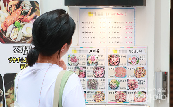 점심시간 서울 중구 명동거리를 찾은 시민이 가게 입구에 붙어 있는 메뉴판을 보고 있다. 사진=서울와이어 DB