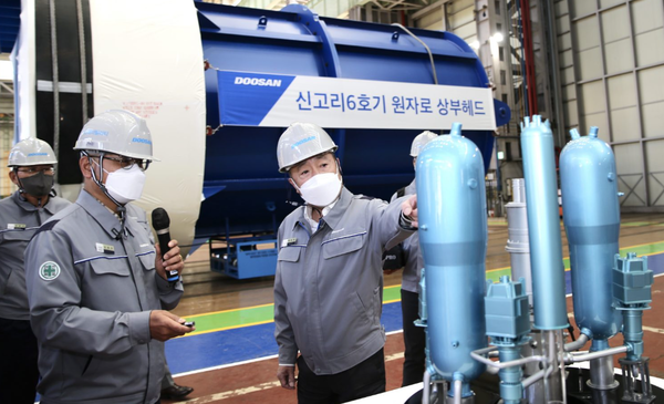 박정원 두산그룹 회장(가운데)이 지난 15일 경남 창원 두산에너빌리티 본사를 찾아 원자력공장 내 원자로 헤드 앞에서 모형을 살피고 있다. 사진=두산그룹 제공