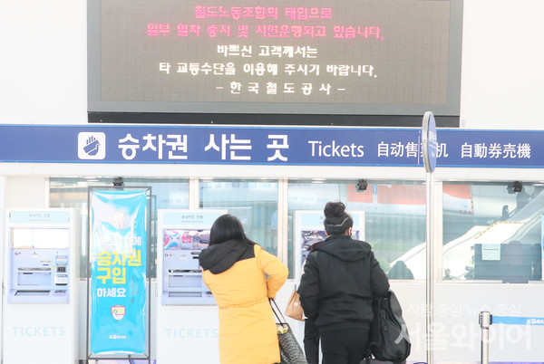 시민들이 전광판에 뜬 열차 지연 알림을 보고 있다.