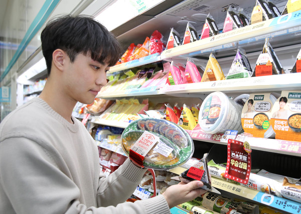 모델이 GS25 편의점에서 도산분식 명란마요삼각라이스 삼각김밥과 비빔면세트를 살펴보고 있다. 사진=GS리테일 제공