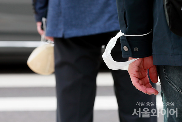 실외 마스크 착용 의무가 전면 해제된 26일 오전 서울 광화문역 일대에서 시민들이 마스크를 팔목에 걸고 이동 하고 있다.