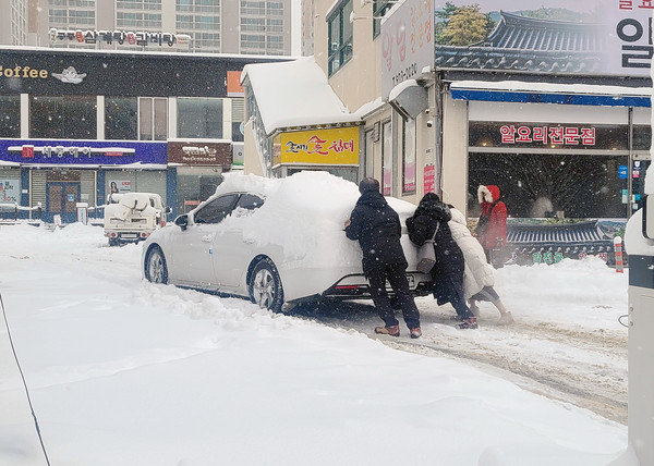 지난 23일 광주광역시에 내린 기록적인 폭설로 도로에 고립된 차량을 시민들이 직접 밀고있다. 사진=연합뉴스 제공