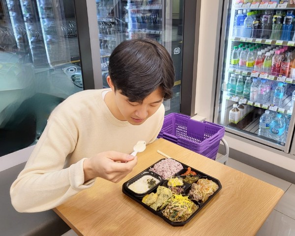 모델이 편의점 CU에서 떡국 도시락을 시식하고 있다. 사진=BGF리테일 제공
