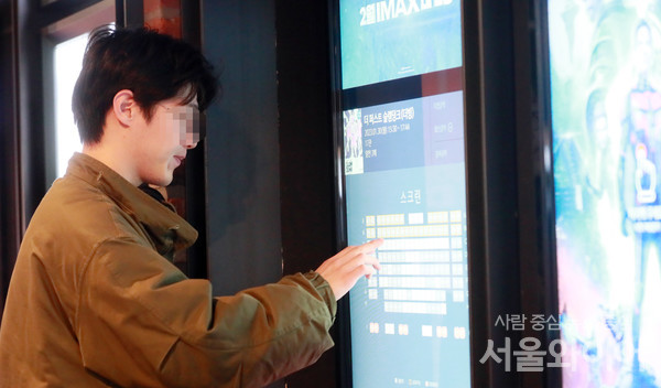 정부가 실내 마스크 착용 의무를 해제한 첫 날 서울시내 영화관을 찾은 한 시민이 영화를 예매하고 있다.