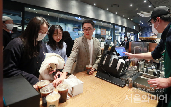 서울시내 커피 전문점을 찾은 시민들이 음료를 받고 있다.