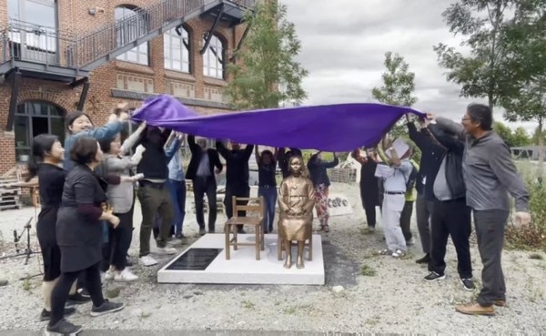 독일 카셀대 총학생회와 시민들이 지난해 7월 카셀대 캠퍼스 내 평화의 소녀상 영구설치 제막식에서 막을 들어 올리고 있다 [사진=연합뉴스]