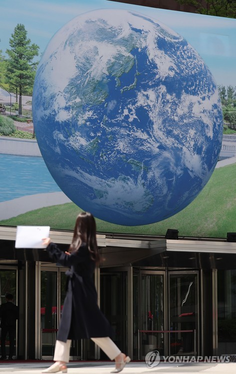 지구의 날을 하루 앞둔 21일 오후 서울 중구 세종대로의 한 건물 외벽에 걸린 지구 그림 앞으로 시민이 지나가고 있다. (사진=연합뉴스)