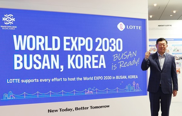 신동빈 롯데그룹 회장이 부산 엑스포를 홍보하는 대형 스크린 앞에서 기념 촬영하고 있다. 사진=롯데지주 제공