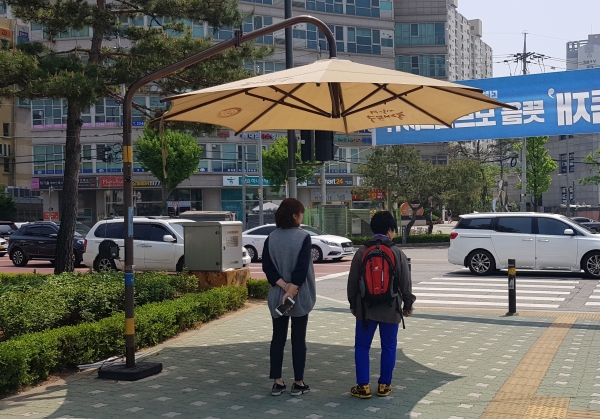 동대문구 전농사거리에 설치된 ‘무더위 그늘막’에서 신호를 기다리는 주민들이 햇볕을 피하고 있다(사진=동대문구)