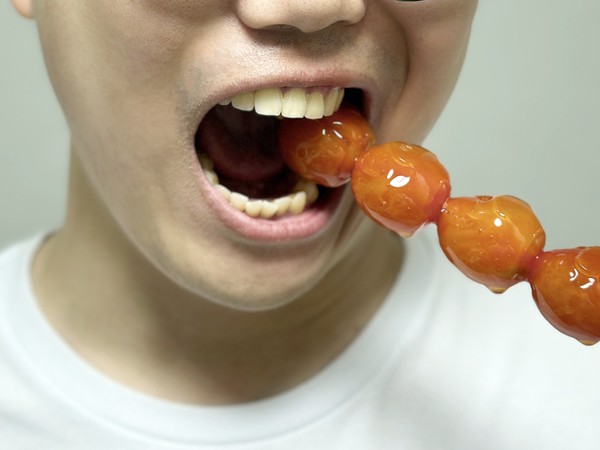 한 남성이 탕후루의 딱딱한 설탕 코팅을 베어물고 있다. 사진=자생한방병원 제공