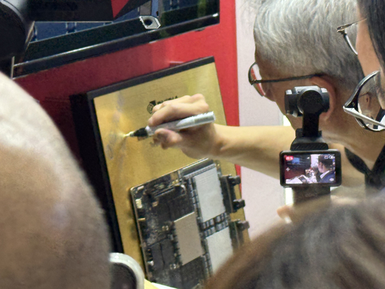 젠슨 황 엔비디아 최고경영자(CEO)가 지난달 20일 대만에서 개막한 정보기술(IT) 전시회 '컴퓨텍스 2025'에서 SK하이닉스 부스를 찾아 서명하고 있다. 사진=연합뉴스