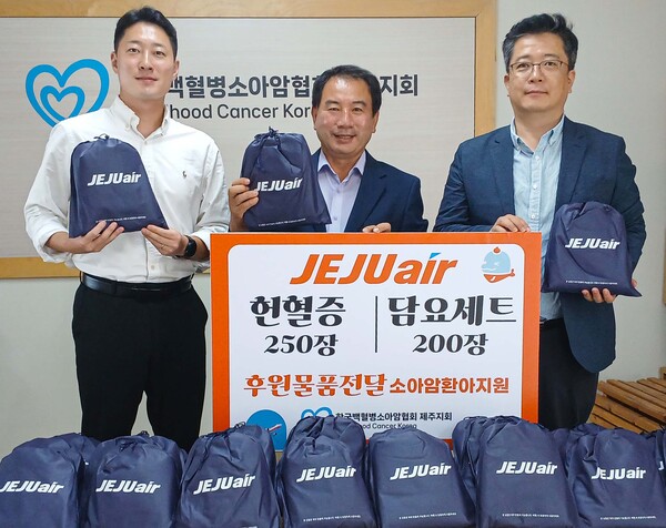 제주항공 김정제 산업안전보건팀장(오른쪽)이 15일 한국백혈병소아암협회 고경남 제주지회장(가운데)에 헌혈증과 담요 등 여행용 키트를 전달한 뒤 기념촬영을 하고 있다. 사진=제주항공